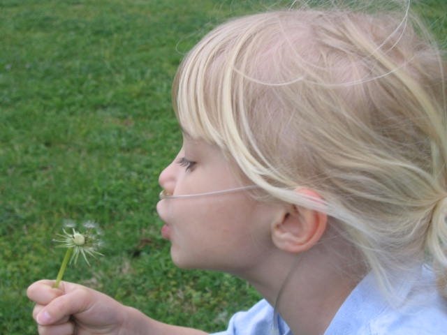 Julia blowing dandelions in the yard