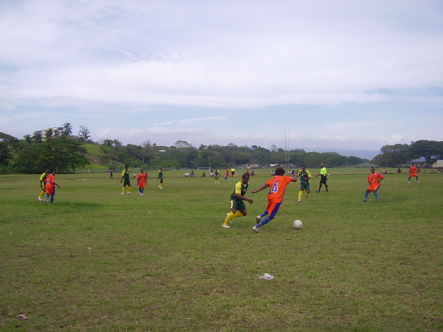 Santos FC Midfielder Mike Hui (in orange jersey) with the ball up against a LAS United FC player