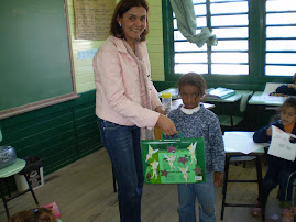 A professora Rejane entregando a Maletinha Mágica para a aluna Vitória.