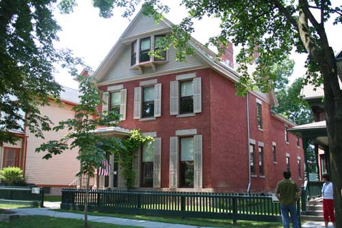 Red brick two-and-a-half-story house with beige trim and shutters