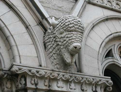 Carved stone buffalo statue head with round friendly eyes, coming out of a building wall