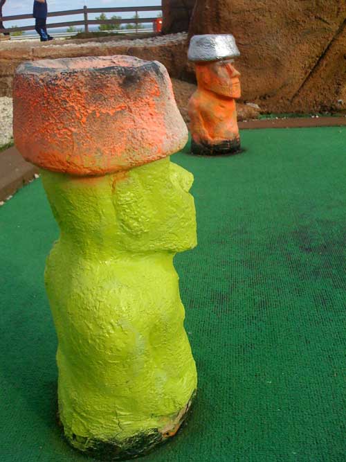 Yellow and orange moai statues on a green