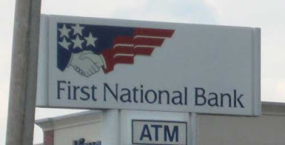 Bank sign whose logo is a handshake, where the sleeve of one hand is made up of red stripes and the sleeve of the other is blue with white stars (a flag reference)